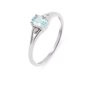 Bague Or Blanc 375 Topaze bleue traitée Ovale 6x4mm diamant Cette bague est composée : 1 Topaze bleue traitée Ovale 0.5 ca...